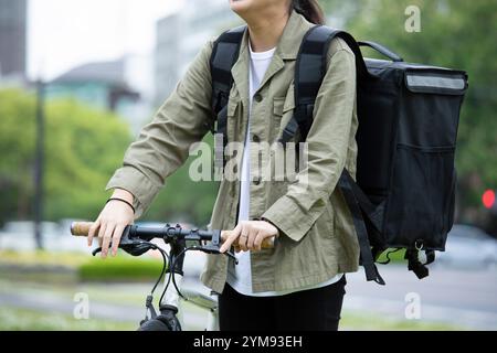 Eine junge Frau, die Pakete mit dem Fahrrad liefert Stockfoto