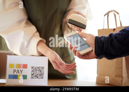 Hände an der Kasse mit einem Smartphone, um eine Zahlung zu tätigen Stockfoto