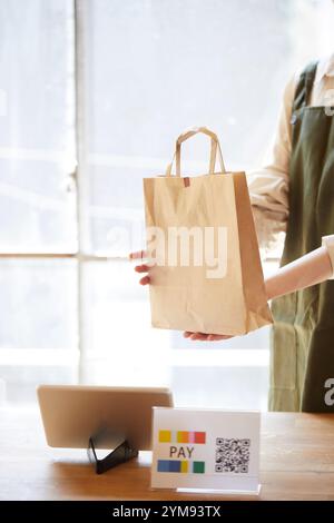 Weibliche Ladeninhaberin an der Kasse mit bargeldloser Zahlung Stockfoto