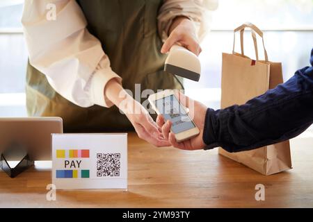 Hände an der Kasse mit einem Smartphone, um eine Zahlung zu tätigen Stockfoto