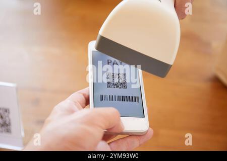 Hände an der Kasse mit einem Smartphone, um eine Zahlung zu tätigen Stockfoto