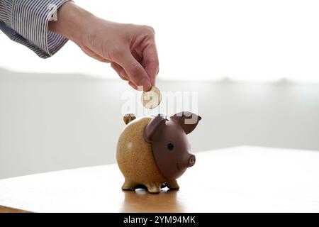 Frau, die Münzen in die Schweinebank in der Hand steckt Stockfoto