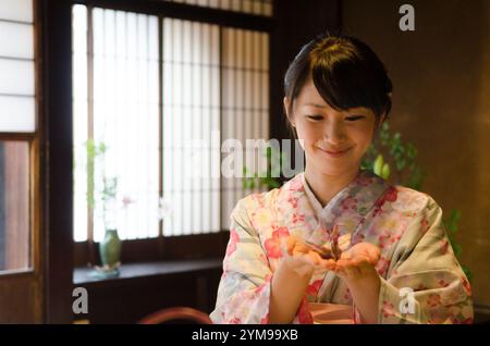 Frau im Kimono mit Origami-Kranichen in der Hand Stockfoto