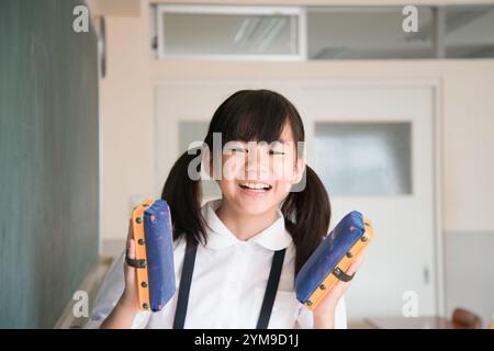 Grundschulmädchen hält Tafelradierer in beiden Händen Stockfoto