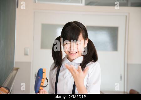 Grundschulmädchen hält Tafelradierer Stockfoto