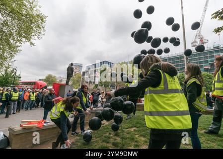 London, Großbritannien. April 2017. 43 schwarze Ballons, einer für jeden der im letzten Jahr getöteten Arbeiter, wurden am Ende der Internationalen Arbeiter&#8217; Memorial Day-Kundgebung an der Statue eines Bauarbeiters auf Tower Hill freigelassen, um 500 in den letzten zehn Jahren, hauptsächlich in der Bauindustrie, sowie an Verletzte, Behinderte und Unwohlsein, fast alle durch vermeidbare Zwischenfälle. In seiner Mitte stand ein Sarg mit Stiefeln, Schutzhelm, hochauflösendem tabard und Schutzbrille, umgeben von weiteren Helmen, einer für jeden der 43 Arbeiter, die dieses Jahr getötet wurden. Der Slogan für den Stockfoto