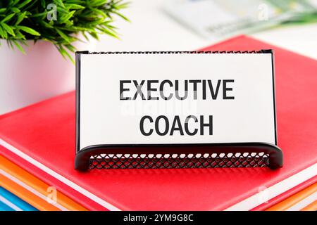 Geschäftskonzept. Der Satz, der Text, das Wort EXECUTIVE COACH stehen auf einer weißen Visitenkarte in einem Ständer auf einem Business-Notebook. Stockfoto