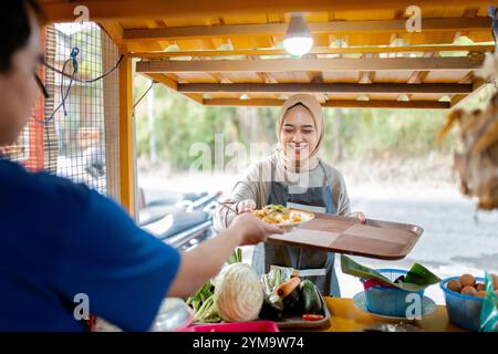 Ein fröhlicher Verkäufer, der frisches und köstliches Essen auf einem lebhaften Straßenmarkt serviert Stockfoto