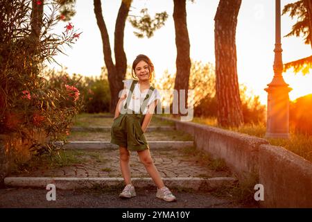Porträt eines kleinen glücklichen Mädchens, das im Park steht und in die Kamera schaut Stockfoto