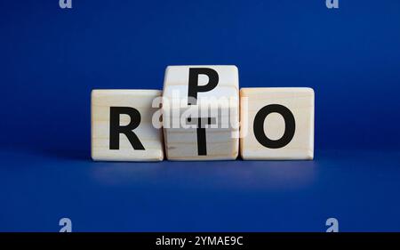 RPO vs. RTO-Symbol. Holzwürfel mit den Worten RTO bis RPO. Wunderschöner tiefblauer Hintergrund. Geschäftskonzept. Kopierbereich Stockfoto