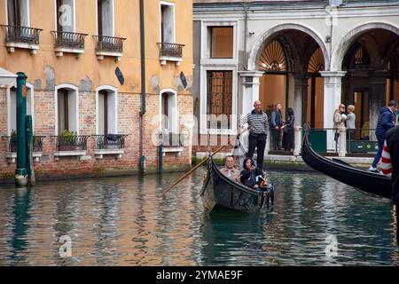 Venedig, Italien;17. Oktober 2024: An einem sonnigen Tag in Venedig navigieren Gondoliere fachmännisch durch die malerischen Kanäle der Stadt und zeigen eine Tradition Stockfoto