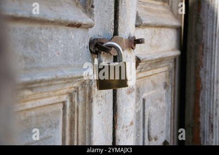 Nahaufnahme des alten Vorhängeschlosses an dem alten, verfaulten, verlassenen Holztor. Rostig, alt, Holztor, Tür, altes Vorhängeschloss Stockfoto