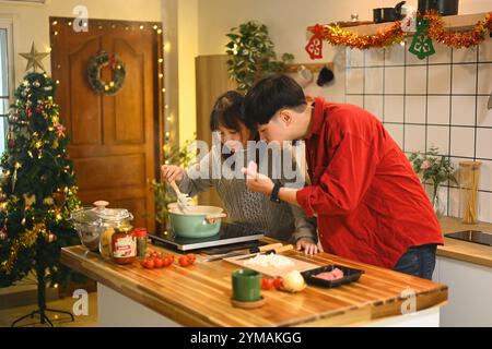 Attraktives junges Paar, das am Weihnachtsabend in der Küche Abendessen zubereitete Stockfoto