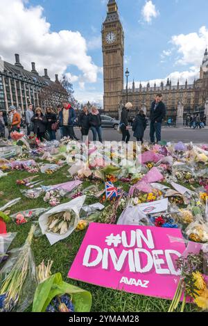 April. Zehn Tage nach dem Terroranschlag in Westminster halten die Menschen immer noch an, um die Blumen für die Opfer entlang der gesamten Front des Parliament Square zu sehen und zu fotografieren. Ein Avaaz Poster trägt die Nachricht '#UNGETEILTE' Stockfoto