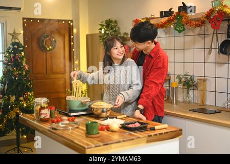 Attraktives junges Paar, das am Weihnachtsabend in der Küche Abendessen zubereitete Stockfoto