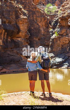 Ein Paar, das am Rand eines Wasserfalls steht und den Blick auf eine Schlucht im Mutawintji National Park im Outback New South Wales, Australien, bewundert. Stockfoto