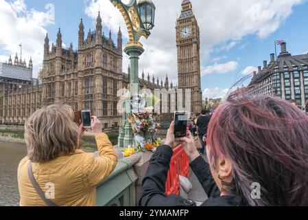 April. Zehn Tage nach dem Terroranschlag in Westminster halten die Menschen immer noch an, um die Blumen für die Opfer rund um die Lampenstandards auf der Waterloo Bridge zu sehen und zu fotografieren. Stockfoto