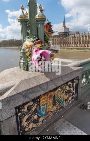 April. Zehn Tage nach dem Terroranschlag in Westminster halten die Menschen immer noch an, um die Blumen für die Opfer rund um die Lampenstandards auf der Waterloo Bridge zu sehen und zu fotografieren. Stockfoto