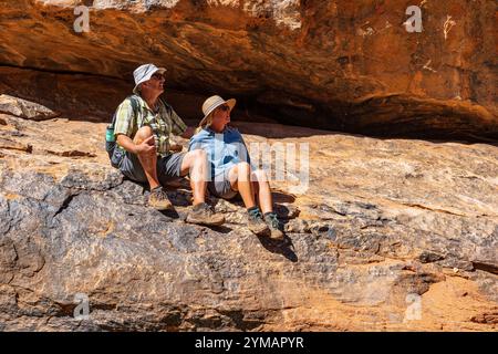 Ein paar Wanderer sitzen auf einem Felsvorsprung und bewundern die Aussicht im Mutawintji National Park im Outback New South Wales, Australien. Stockfoto