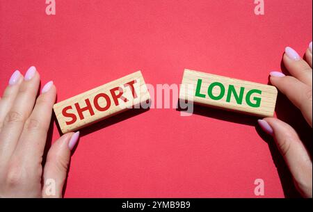 Symbol kurz vs lang. Konzeptwort kurz vs lang auf Holzblöcken. Geschäftsmann Hand. Schöner roter Hintergrund. Business und kurz- vs Langkonzept. Cop Stockfoto