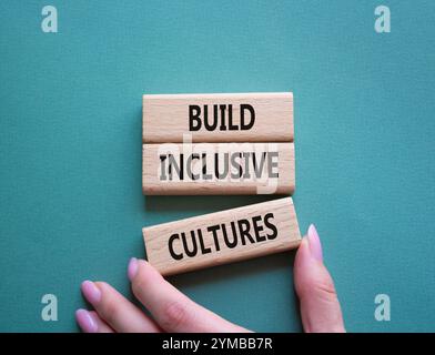 Symbol „integrative Kulturen erstellen“. Holzblöcke mit Wörtern bilden inklusiv-Kulturen. Wunderschöner graugrüner Hintergrund. Geschäftsmann Hand. Business und BU Stockfoto