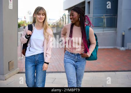Multiethnische Studenten gehen und reden auf dem Campus Stockfoto
