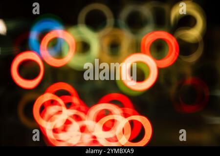 Abstrakte, unscharfe, verschwommene, katadioptrische oder reflektierende Linsen, Donut-förmige Bokeh-Highlights bei Nacht. Stockfoto