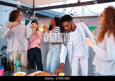 Multiethnische Freunde genießen eine Dachparty mit Pizza und Getränken Stockfoto