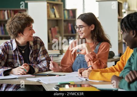 Lächelnde Schüler, die in der Bibliotheksumgebung zusammenarbeiten Stockfoto