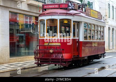 Lissabon, Portugal - 10. November 2024: Eine traditionelle Straßenbahn fährt auf einer Stadtstraße in der Altstadt. Stockfoto