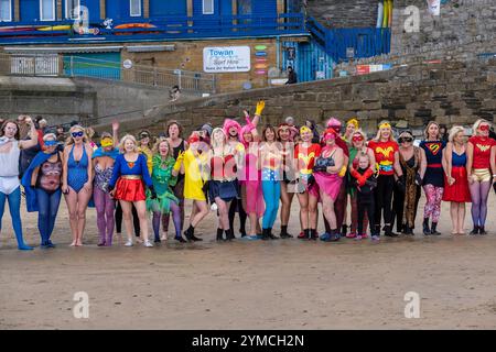 Die Teilnehmer treffen sich am Strand von Towan und bereiten sich auf die jährliche Veranstaltung „Superhero in the Cold“ vor, um Spenden für die britische Krebsforschung zu sammeln. Stockfoto