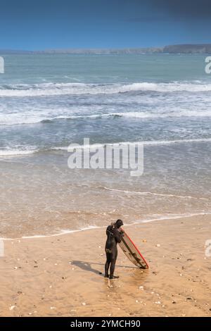 Ein Surfer, der sein Surfbrett vorbereitet, bevor er am Towan Beach in Newquay in Cornwall in Großbritannien surft. Stockfoto
