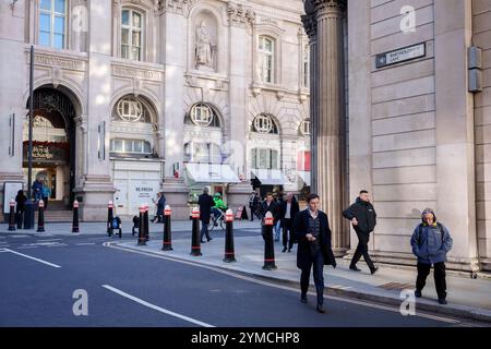 Stadtarbeiter laufen am 20. November 2024 in London, dem Finanzviertel der Hauptstadt, über die Ecke Threadneedle Street und Batholomew Lane, unter der Architektur der Bank of England (rechts). Stockfoto