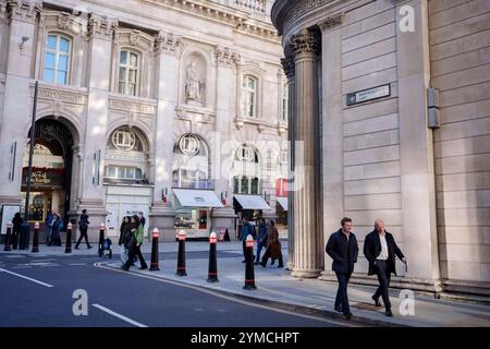 Stadtarbeiter laufen am 20. November 2024 in London, dem Finanzviertel der Hauptstadt, über die Ecke Threadneedle Street und Batholomew Lane, unter der Architektur der Bank of England (rechts). Stockfoto