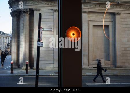 Stadtarbeiter gehen am 20. November 2024 über die Ecke Threadneedle Street und Batholomew Lane, wo die Mauern und Säulen der Bank of England rechts in der City of London, dem Finanzviertel der Hauptstadt, zu sehen sind. Stockfoto