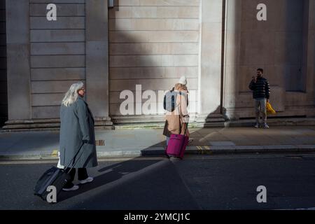 Stadtarbeiter gehen am 20. November 2024 über die Ecke Threadneedle Street und Batholomew Lane, wo die Mauern und Säulen der Bank of England rechts in der City of London, dem Finanzviertel der Hauptstadt, zu sehen sind. Stockfoto