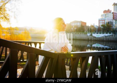 Frau in weißem Pullover, die sich auf die Brücke lehnt Stockfoto