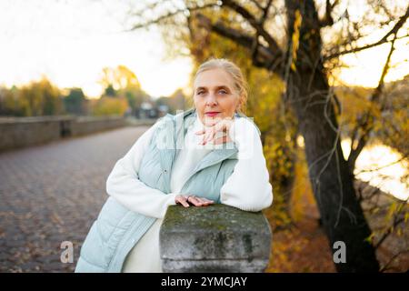 Porträt einer Frau, die sich im Herbst an einer Wand an einer Flußwand lehnt Stockfoto