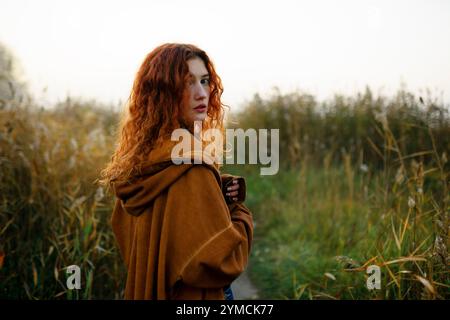 Porträt einer Frau mit rotem Haar, die auf dem Grasfeld steht Stockfoto
