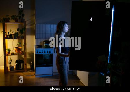 Frau, die nachts vor dem offenen Kühlschrank steht Stockfoto