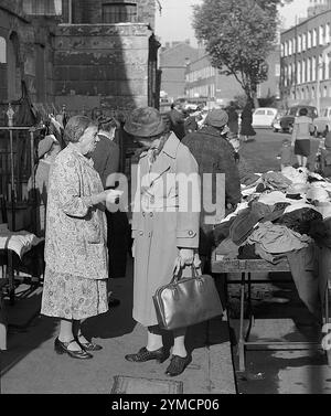 Zwei Frauen unterhalten sich am Second Hand Clothes Market Stand im Londoner East End, 1950er Jahre Stockfoto