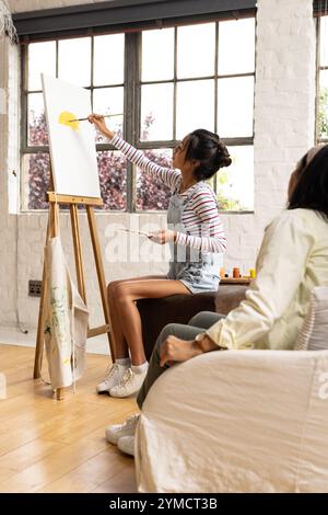 asiatische Teenagerinnen malen zu Hause auf Leinwand und genießen kreative Zeit mit der Familie Stockfoto