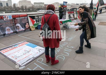 London, Großbritannien. März 2017. Eine Frau schreibt die Botschaft "HP Powered Israeli Dungeon for a Child" bei einer späten Mahnwache anlässlich des Internationalen Frauentages der Menschenrechtsgruppe Inminds im South Bank, wo das WOW – Women of the World Festival gegen die Folter und Misshandlung palästinensischer Frauengefangener in israelischen Gefängnissen stattfindet. Laut der Menschenrechtsgruppe Inminds werden derzeit 65 Frauen, darunter 12 junge Mädchen und 16 Mütter, in von Ratten befallenen israelischen Kerkern festgehalten, in denen Folter Routine ist und die Grundlagen des menschlichen Lebens wie Nahrung, Kleidung, Decken und medizinische Grundversorgung A sind Stockfoto