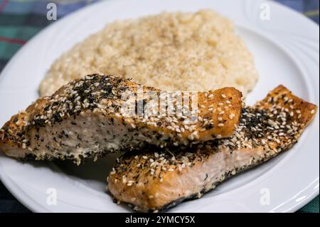 Gegrillte Lachsscheiben mit Sesam, Gewürz und Kräutern auf weißem Teller mit kokiertem Reis Stockfoto