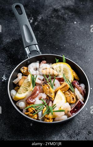 Roher Mix Meeresfrüchte-Cocktail mit Garnelen, Garnelen, Muscheln, Tintenfischen und Tintenfischen in einer Pfanne bereit zum Kochen. Schwarzer Hintergrund. Draufsicht. Stockfoto