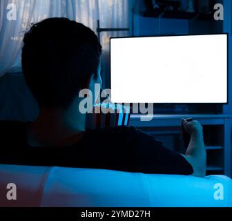 Mann sieht nachts fern, während er Popcorn in seinem Wohnzimmer isst, Konzept eines Mannes, der fernsieht Stockfoto