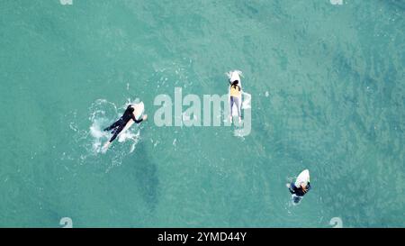 Surfer im Wasser und auf ihren Surfbrettern warten auf ihre nächste Welle an einem Strand in Portugal Stockfoto