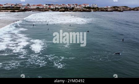 Surfer im Wasser und auf ihren Surfbrettern warten auf ihre nächste Welle an einem Strand in Portugal Stockfoto