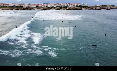 Surfer im Wasser und auf ihren Surfbrettern warten auf ihre nächste Welle an einem Strand in Portugal Stockfoto