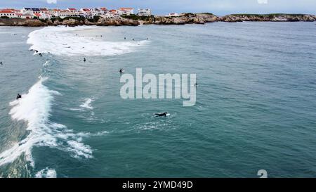 Surfer im Wasser und auf ihren Surfbrettern warten auf ihre nächste Welle an einem Strand in Portugal Stockfoto